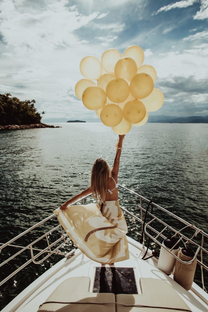 a person holding a bunch of balloons on a boat