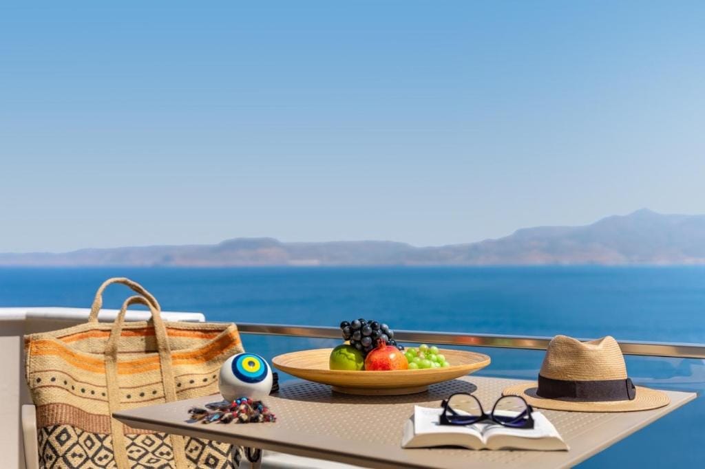 a table with a plate of fruit and a hat on it by a body of water