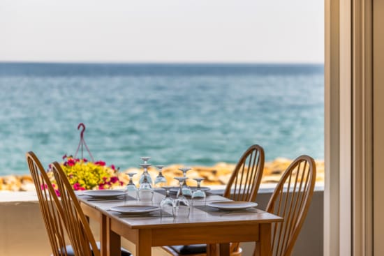 a table with chairs and a view of the ocean