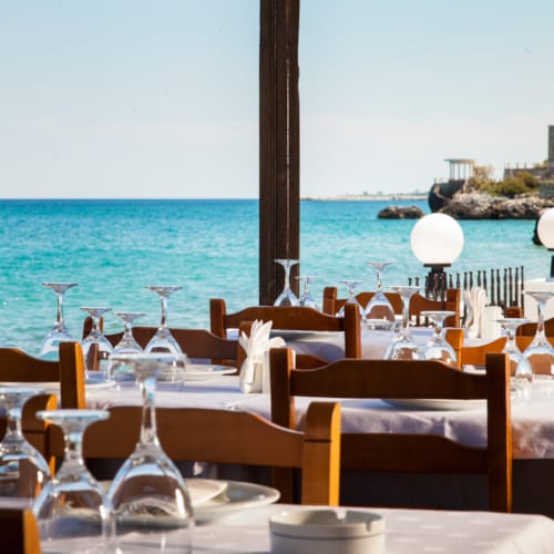 a table with glasses and plates on it by a body of water