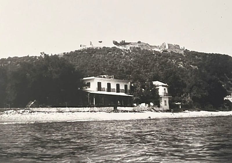 A black-and-white historical photograph of KYMATA Restaurant in Platamonas, taken from a distance, showing the coastal landscape of the area.