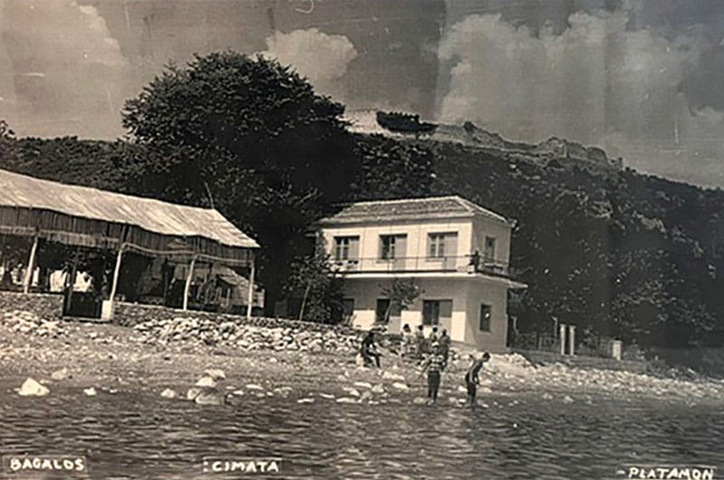 A black-and-white historical photograph of KYMATA Restaurant and Hotel in Platamonas, showing people swimming in front of the beachfront building.