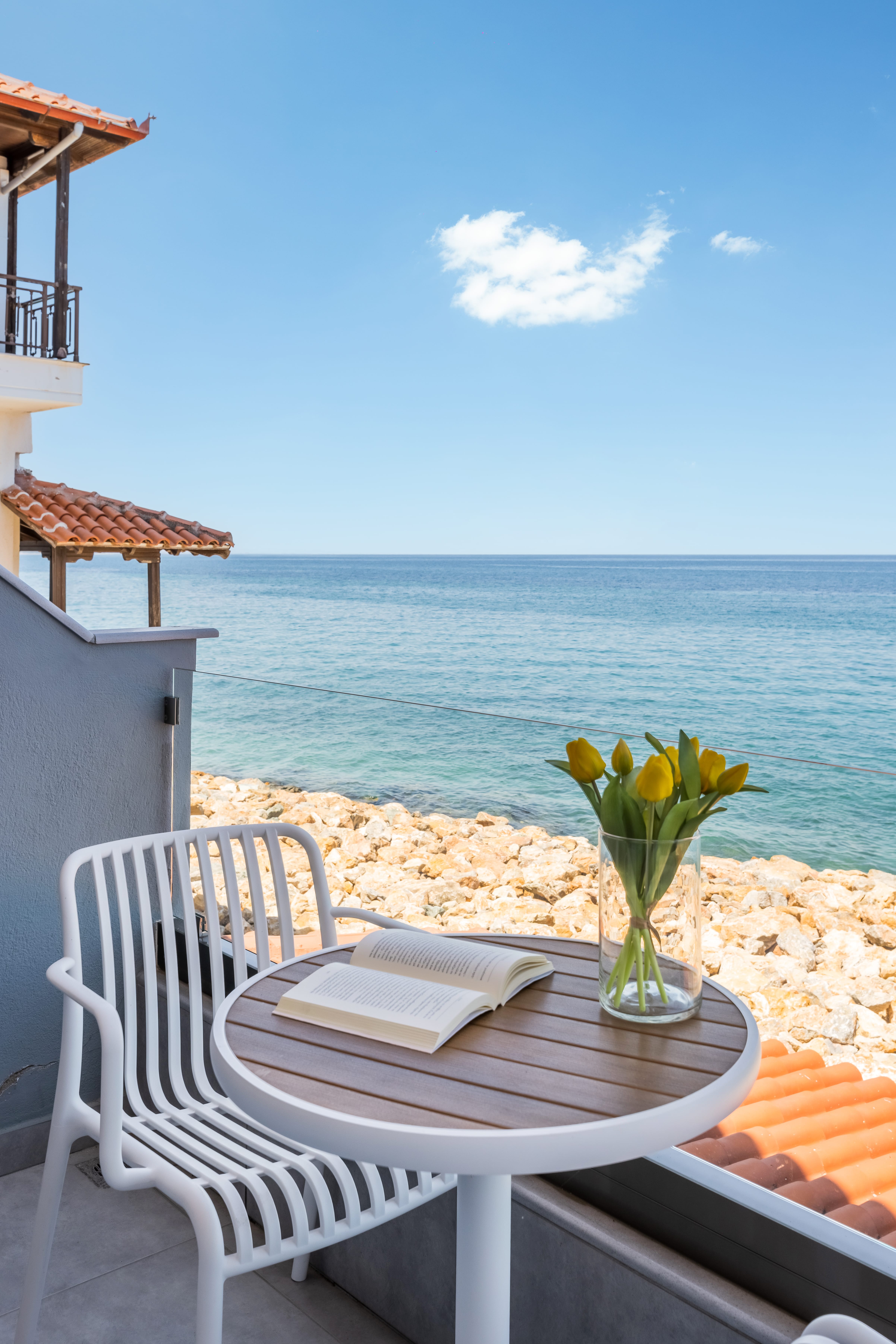 a table with a vase of flowers on a deck overlooking the ocean