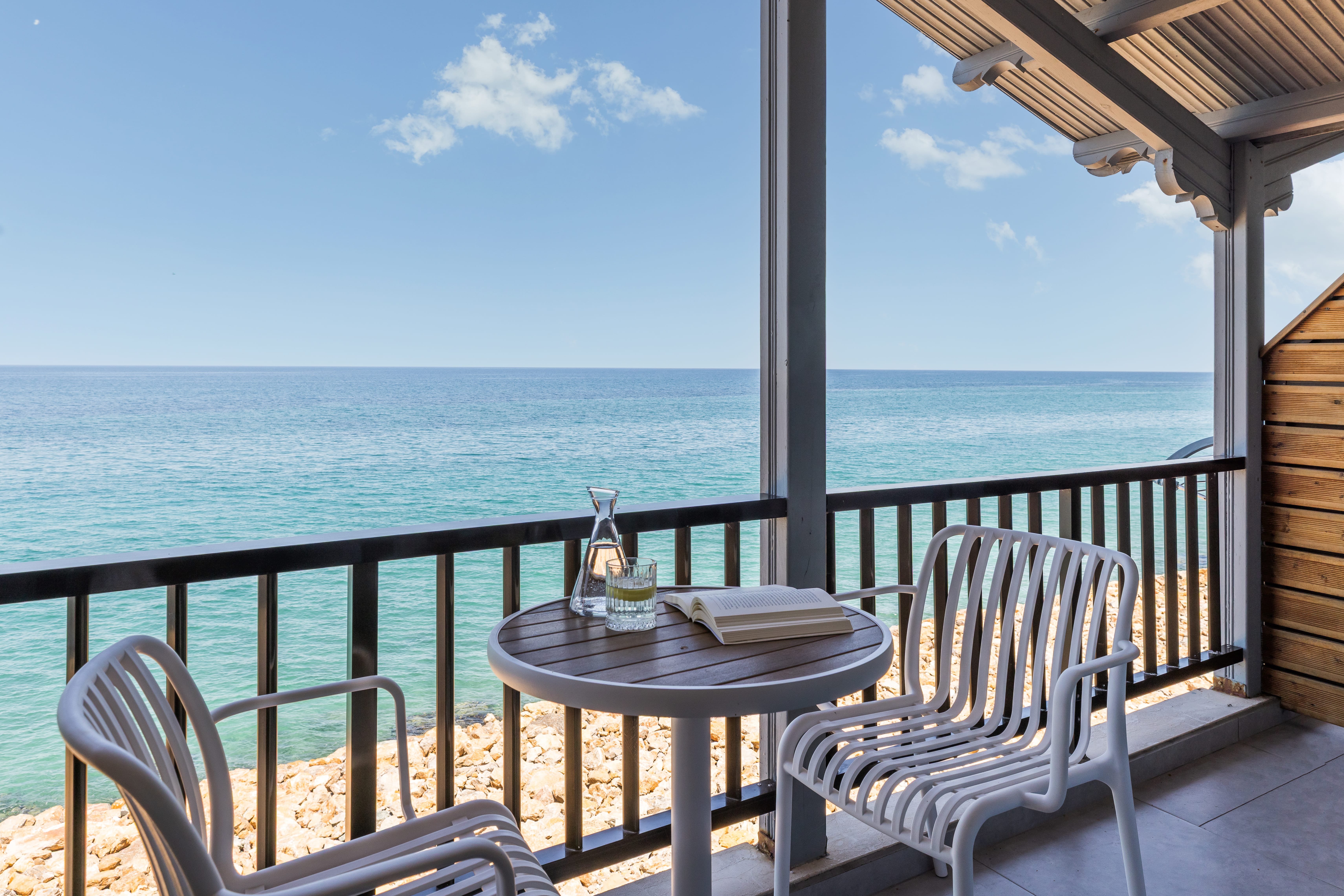 a table and chairs on a deck overlooking the ocean