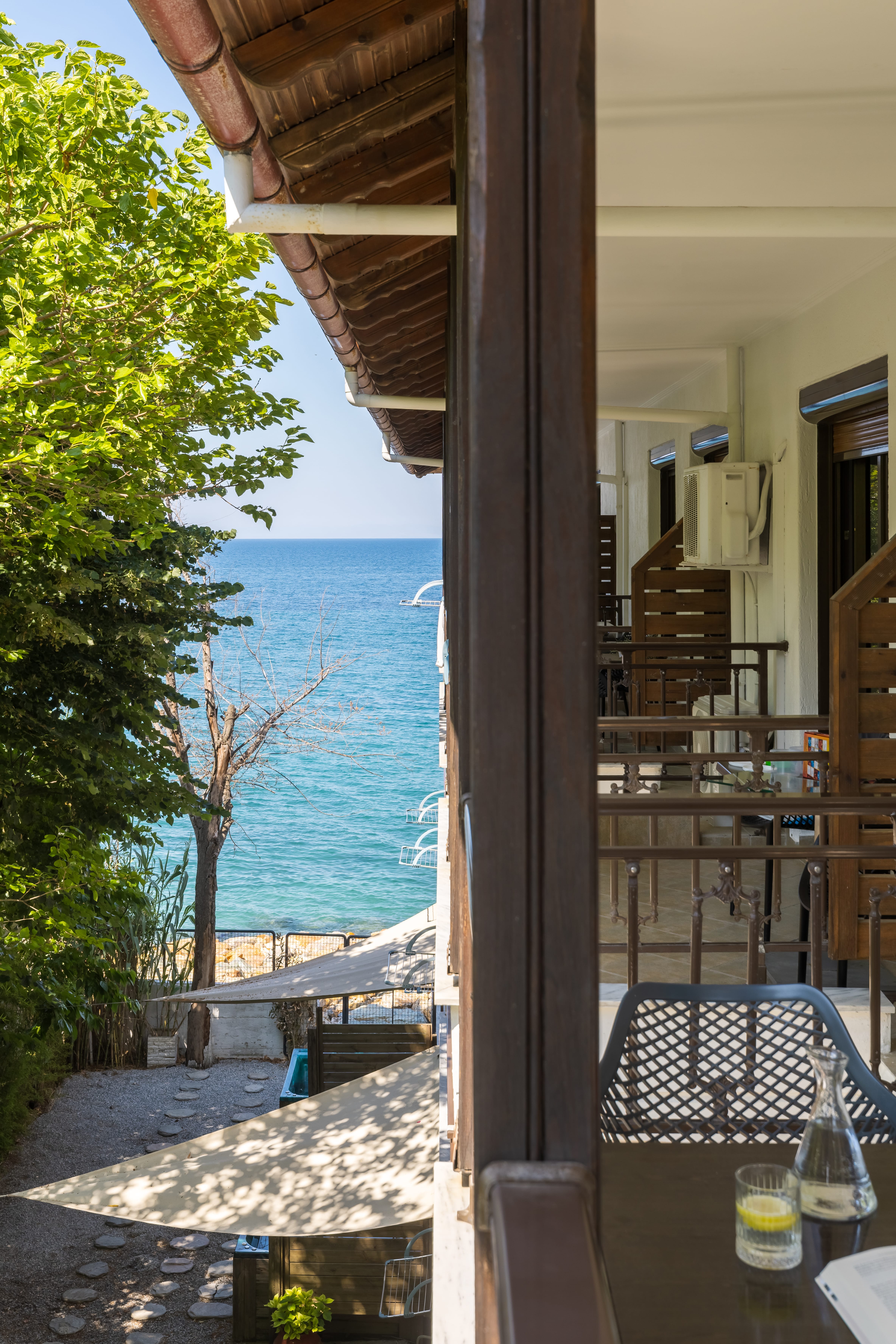 a patio with tables and chairs and a body of water in the background