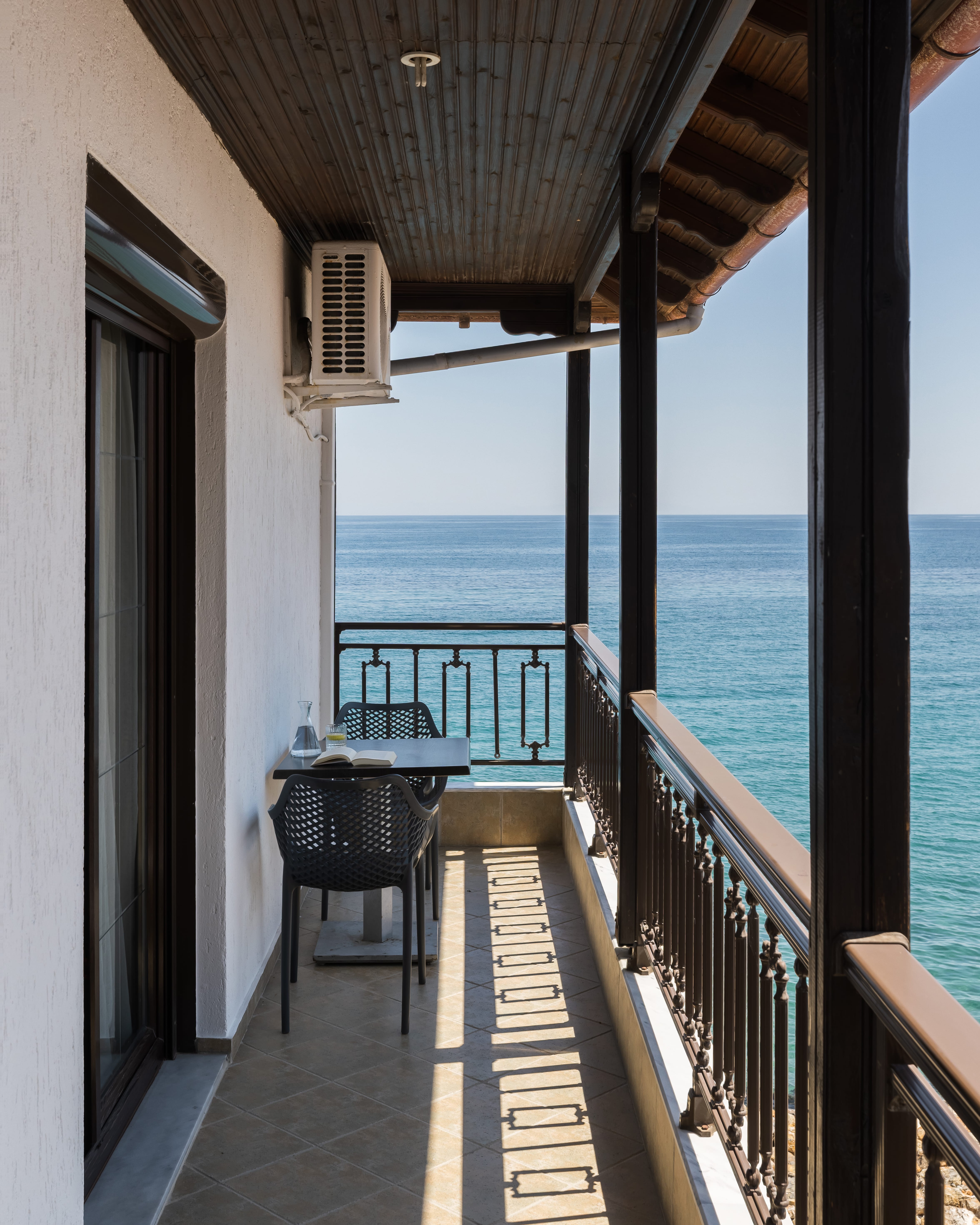 a deck with a table and chairs on it by the water
