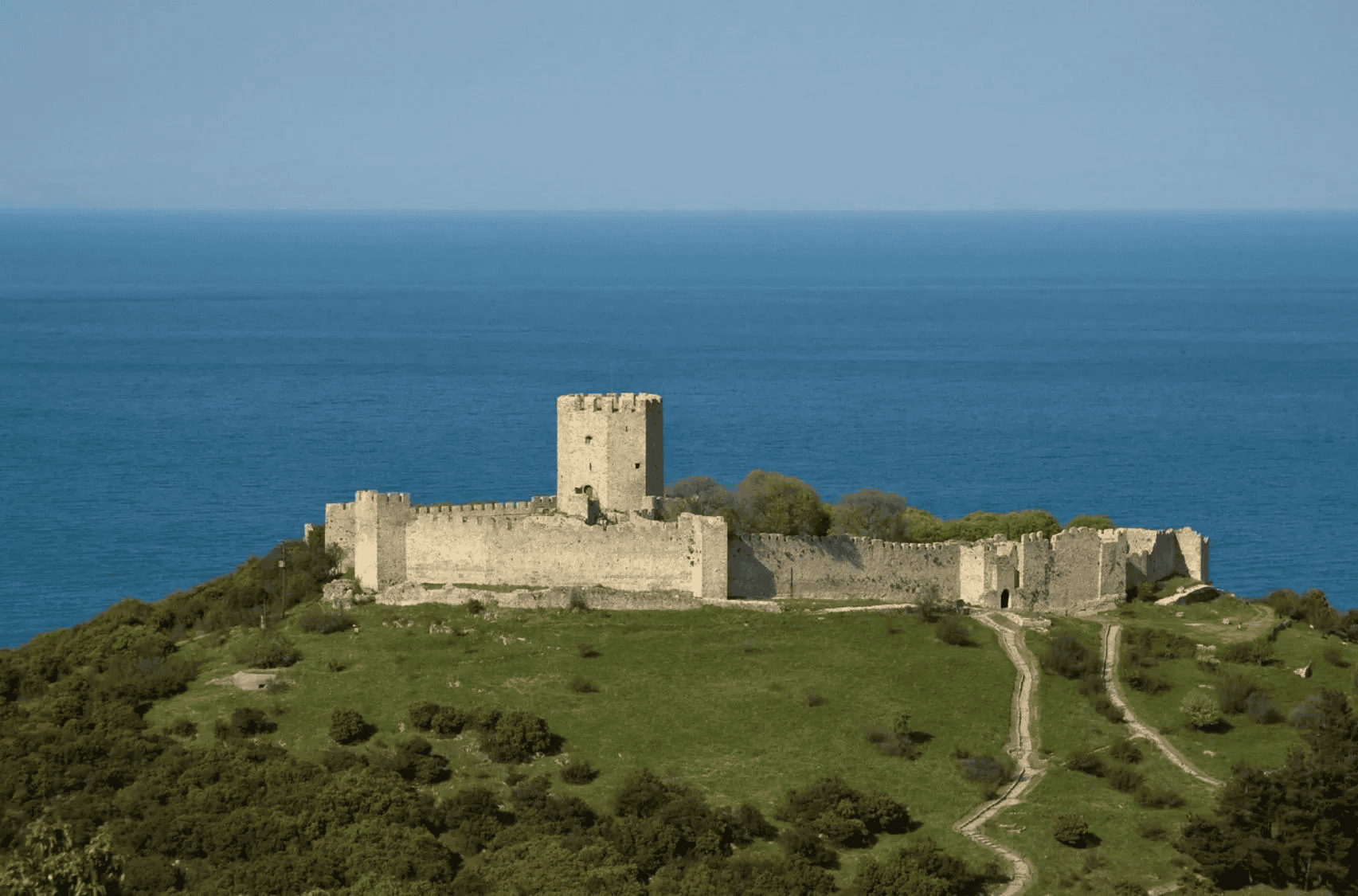 a stone structure on a hill by the ocean