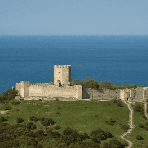 a stone structure on a hill by the ocean