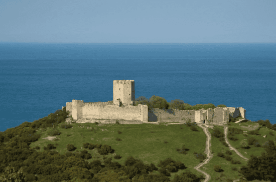 a stone structure on a hill by the ocean