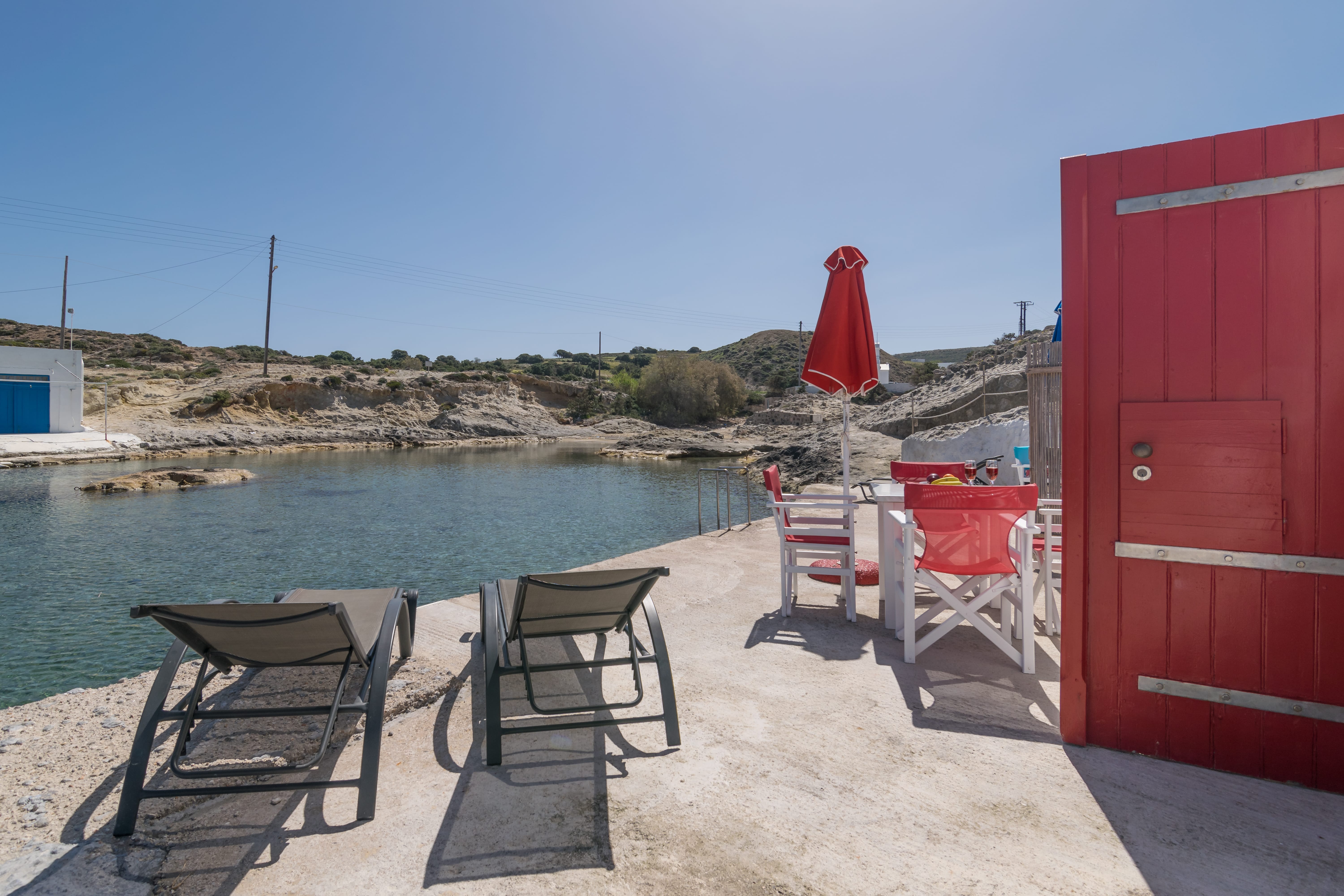 a group of chairs and tables next to a red building and a body of water
