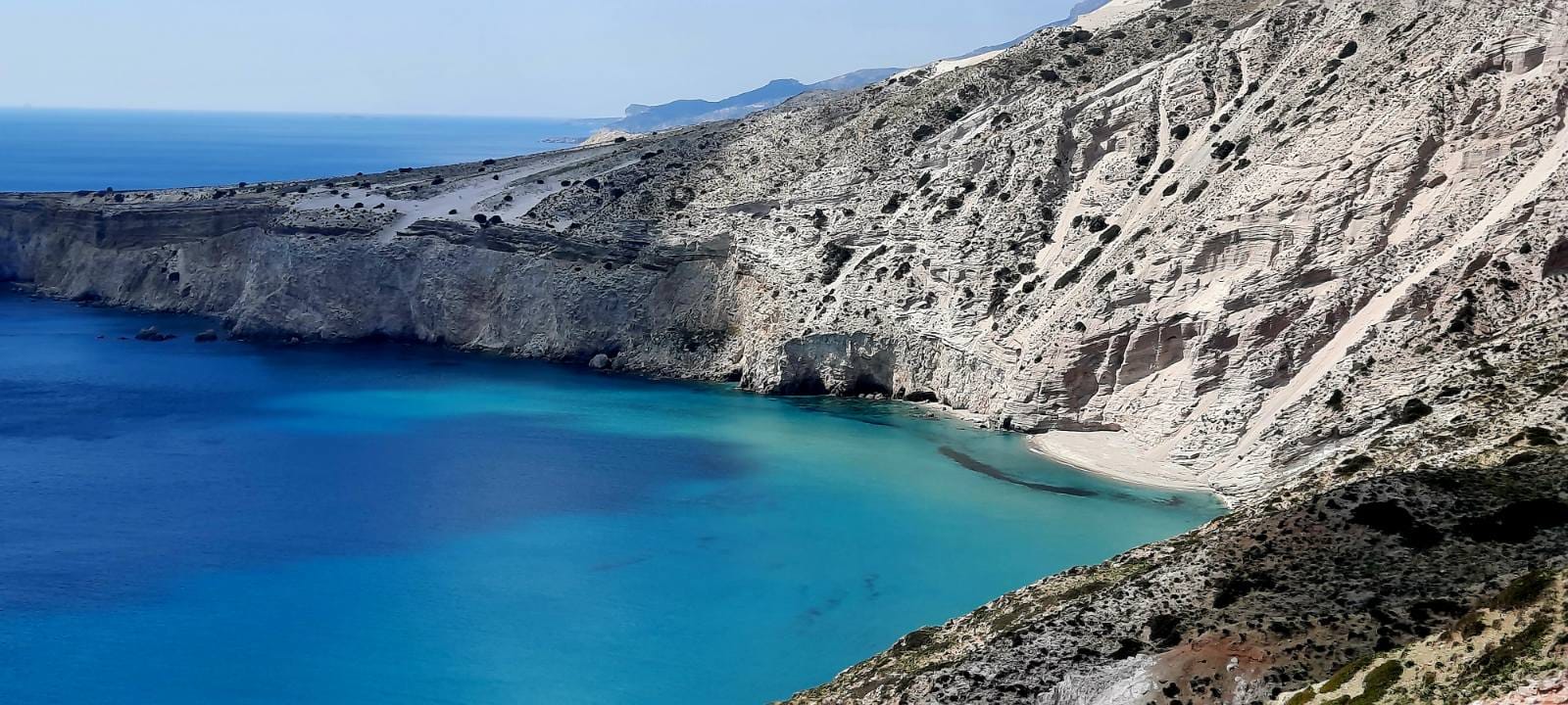 a body of water with a rocky mountain in the background