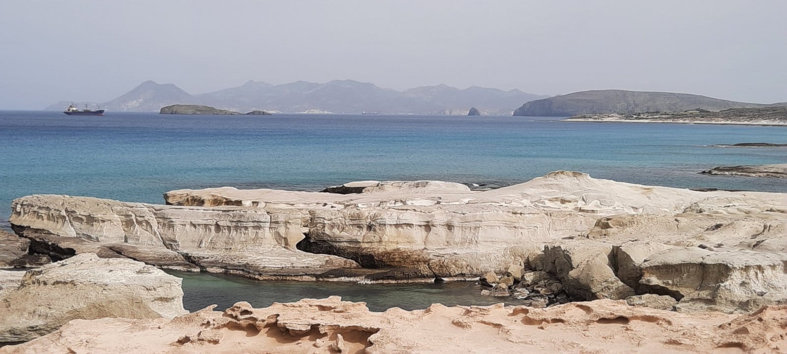 a rocky beach with a body of water in the background