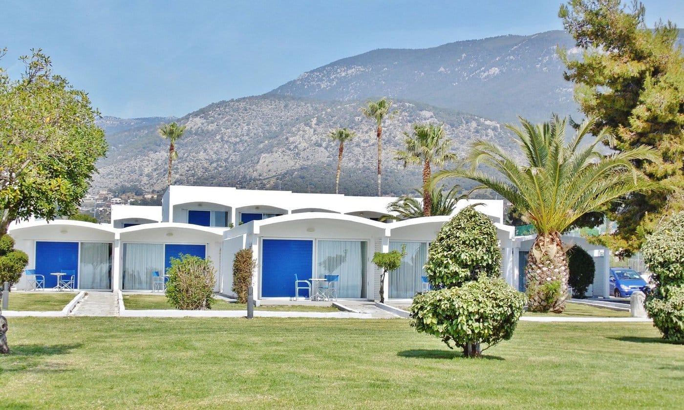 a white house with blue doors and trees in front of it