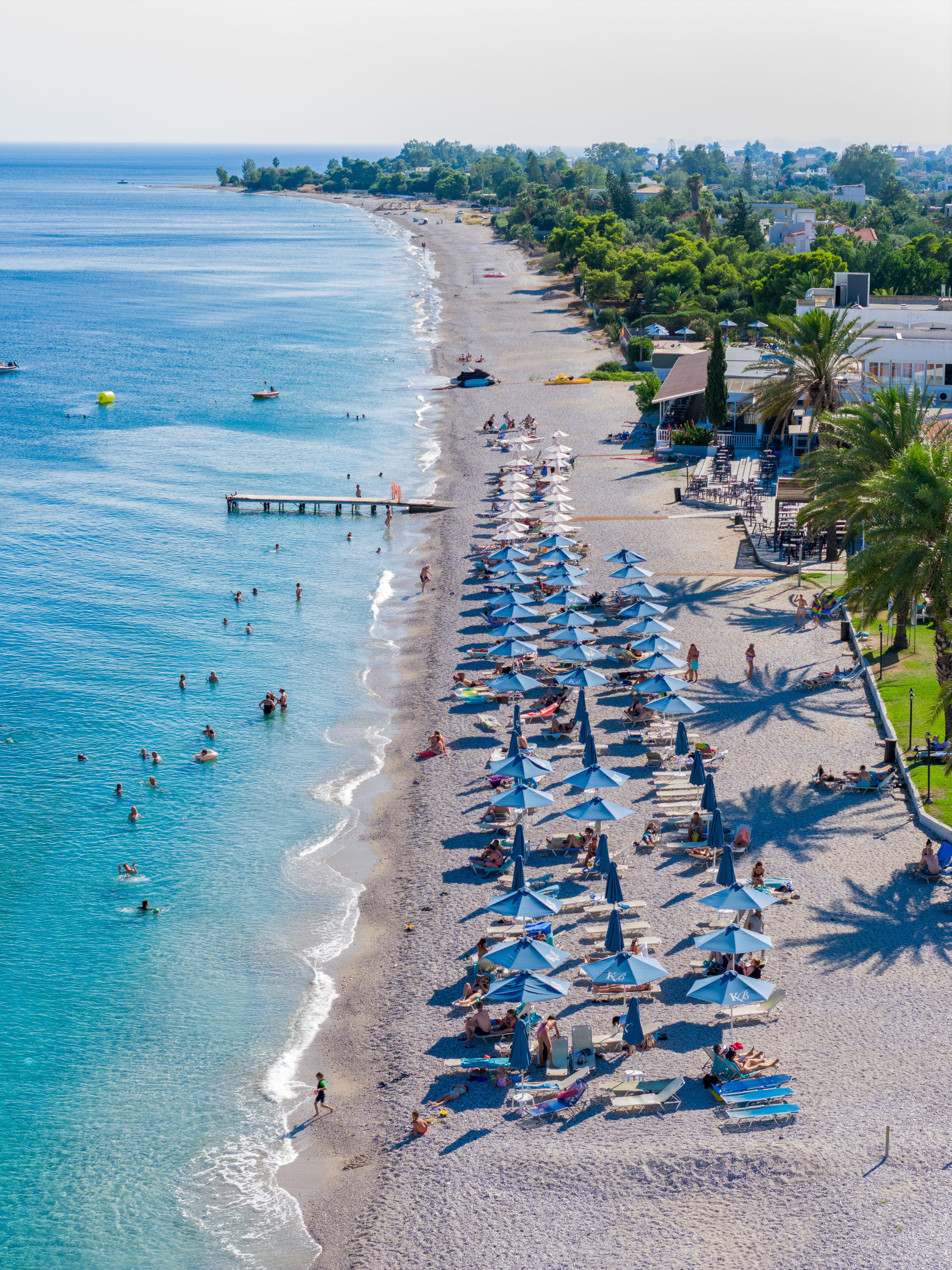 a beach with umbrellas and people swimming in the water
