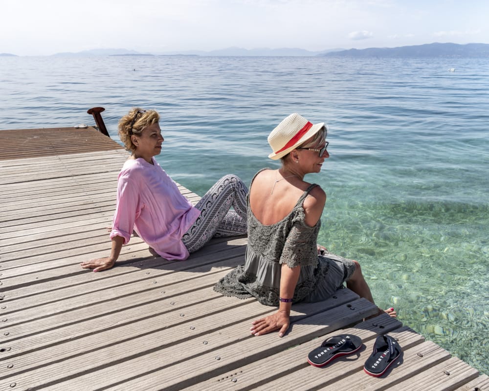 a couple of people sitting on a dock by the water