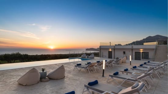 a building with a pool and chairs in front of it