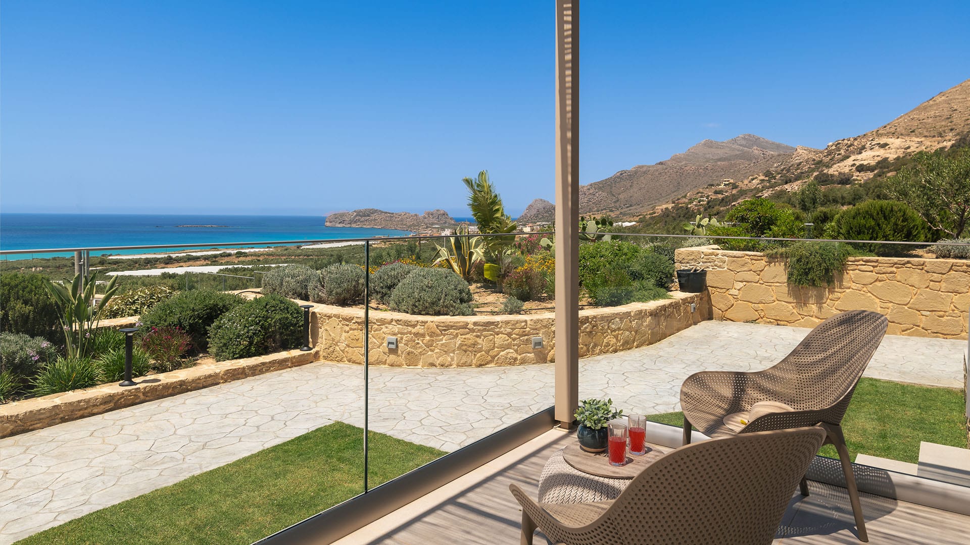 a patio with a pool and a pole with plants and a body of water in the background