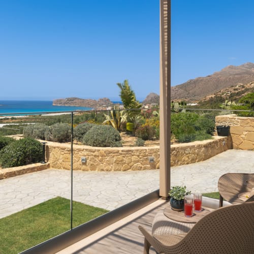 a patio with a pool and a pole with plants and a body of water in the background