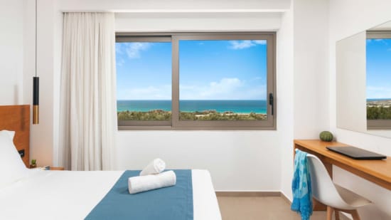 a room with a desk and a window with a view of the ocean