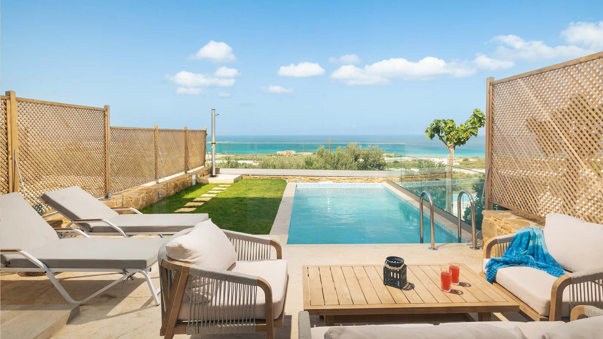 a pool and lounge chairs on a deck overlooking the ocean