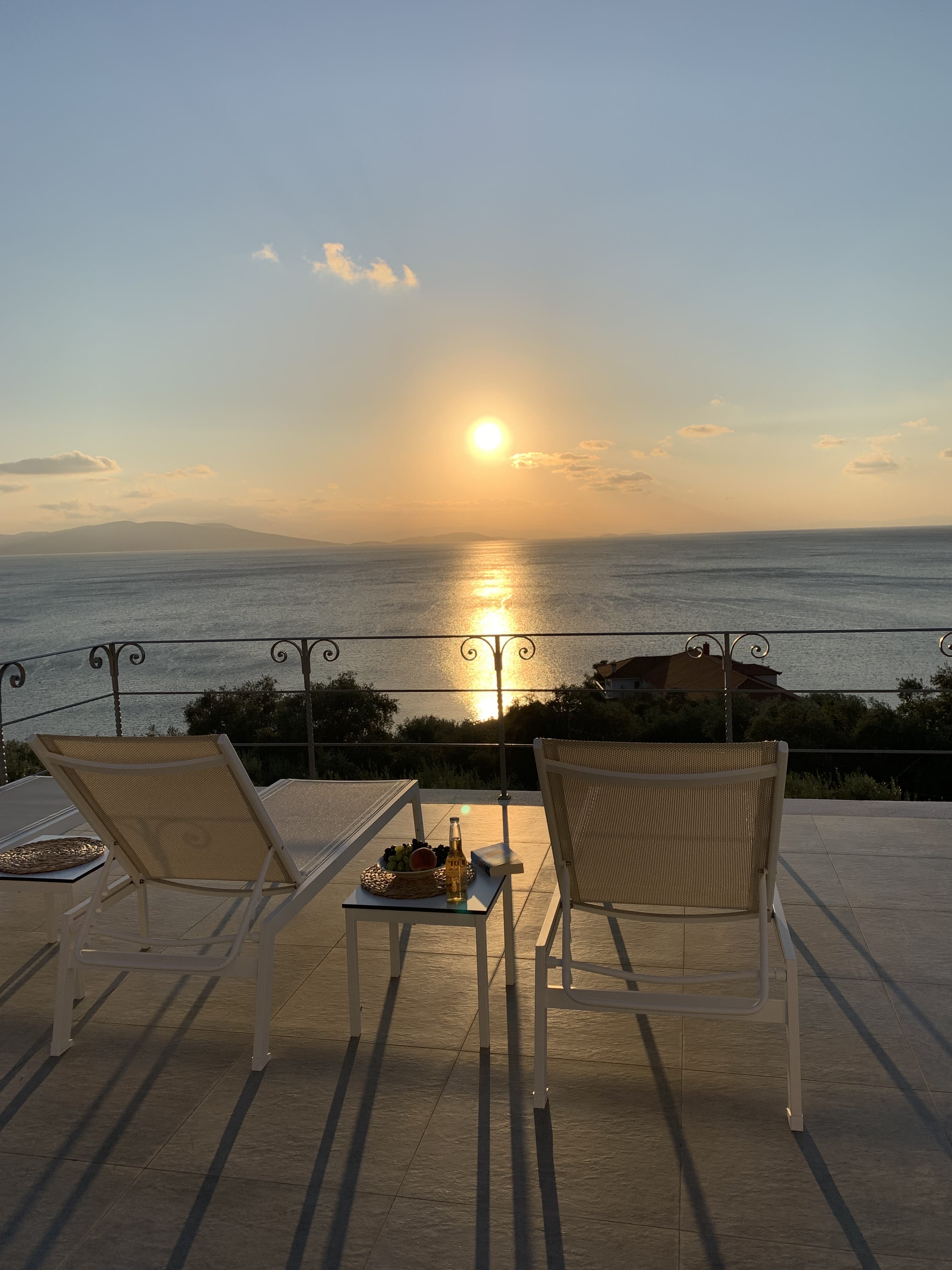 a deck with chairs and a table with a sunset in the background