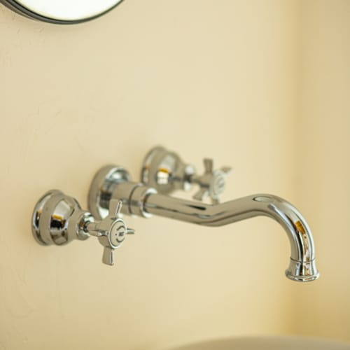 a silver faucet on a white wall