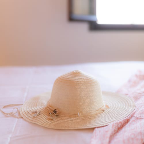 a small tan hat on a bed