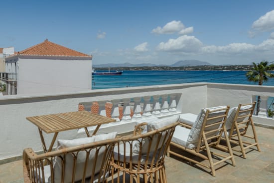 a deck with chairs and tables on it by a body of water