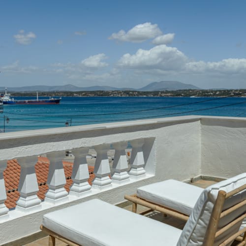 a deck with chairs and tables overlooking a body of water