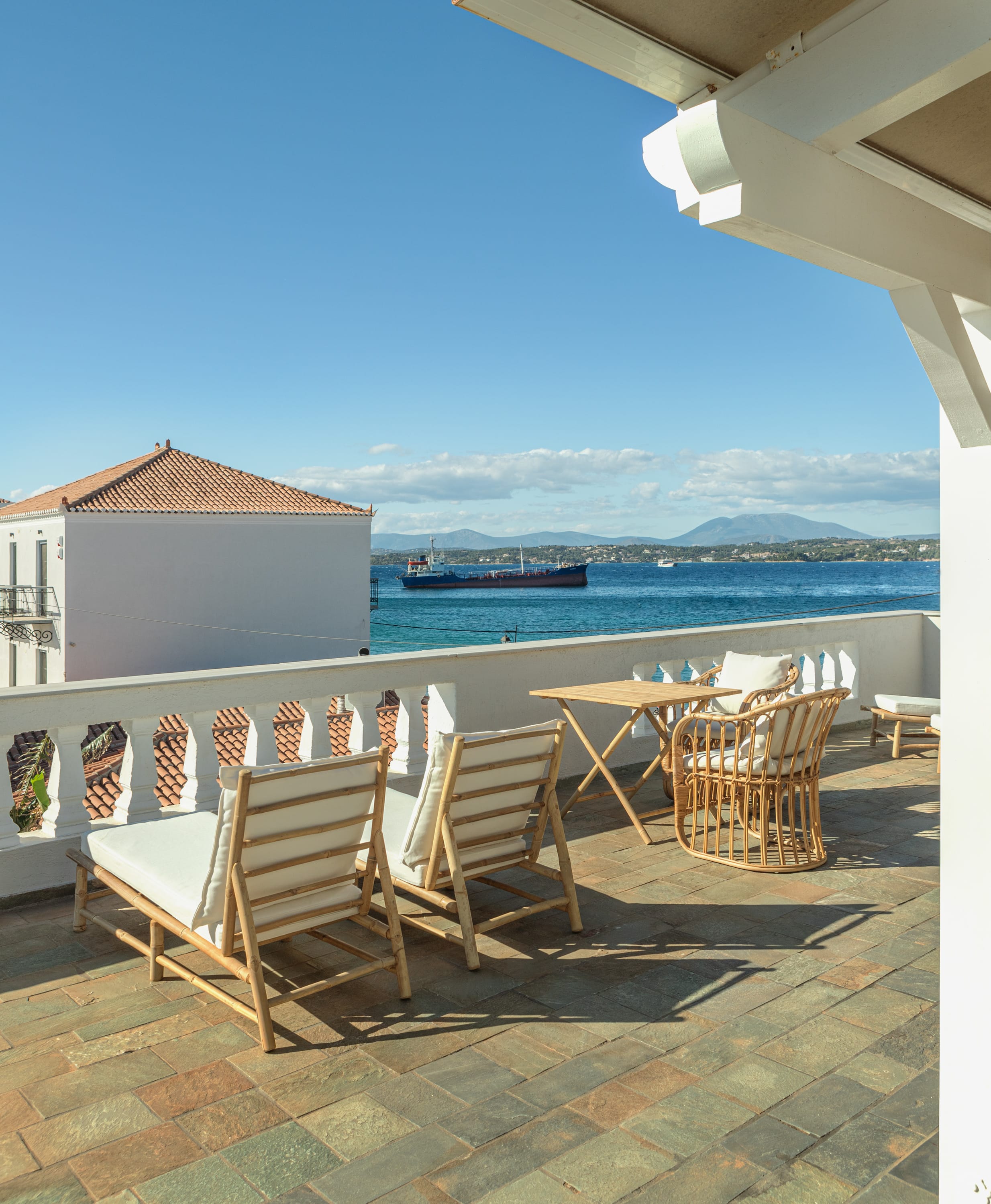 a patio with chairs and tables by a body of water
