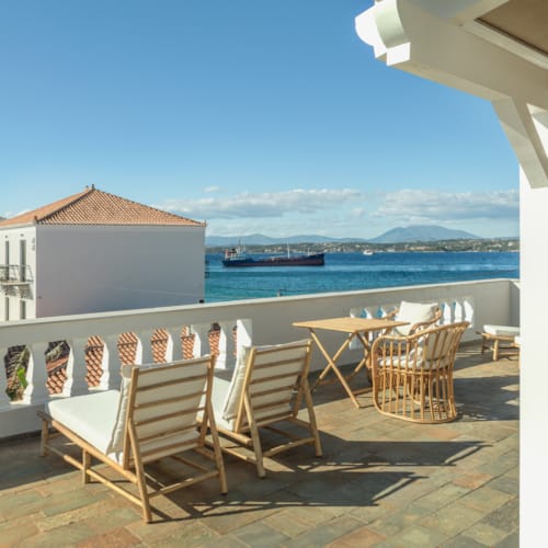 a patio with chairs and tables by a body of water