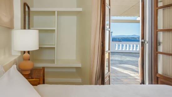 a room with a lamp and a door with a view of the ocean