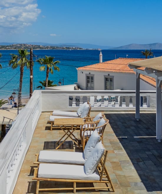 a deck with chairs and tables on it by a body of water