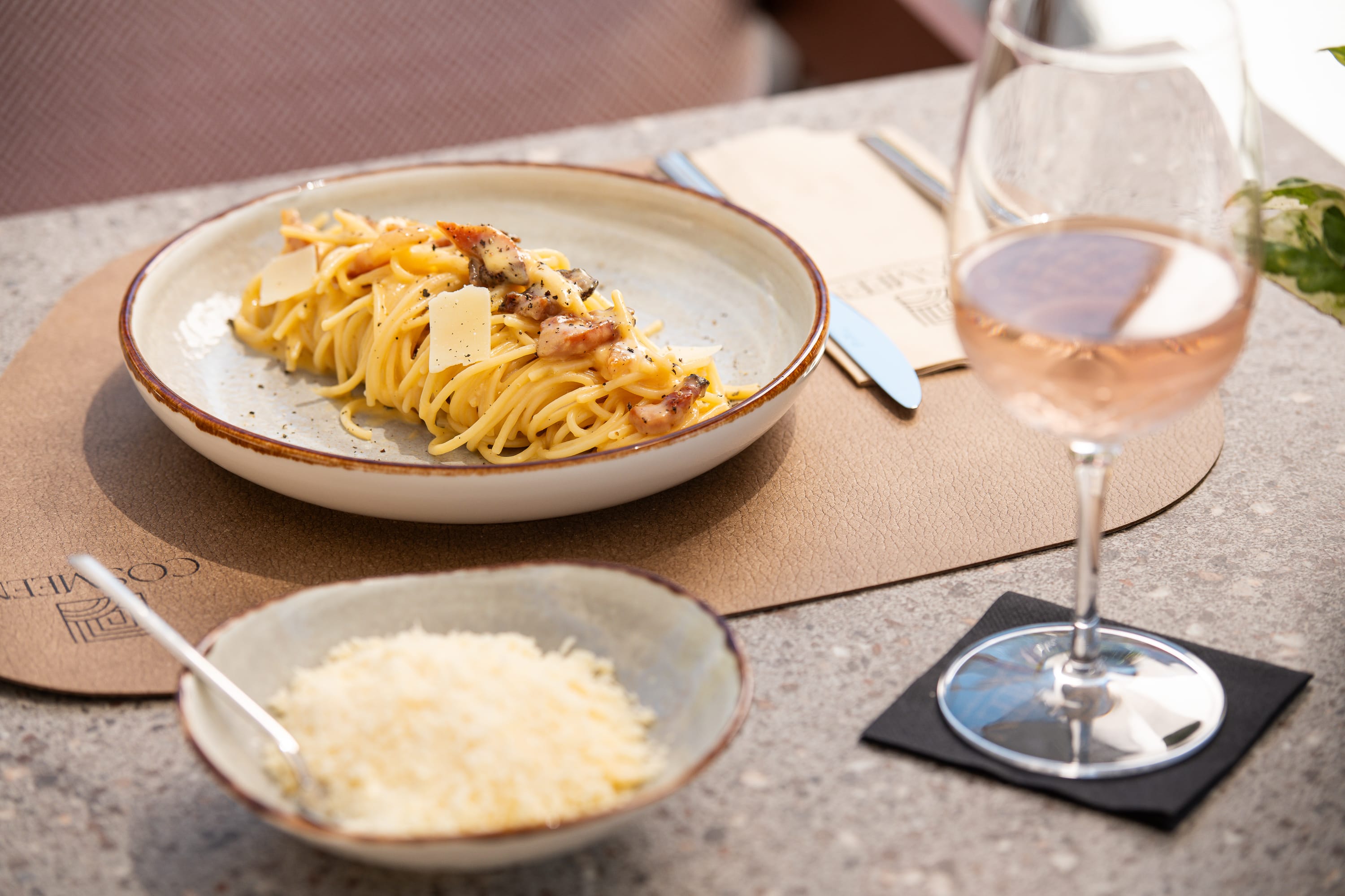 a bowl of food and a glass of wine on a table