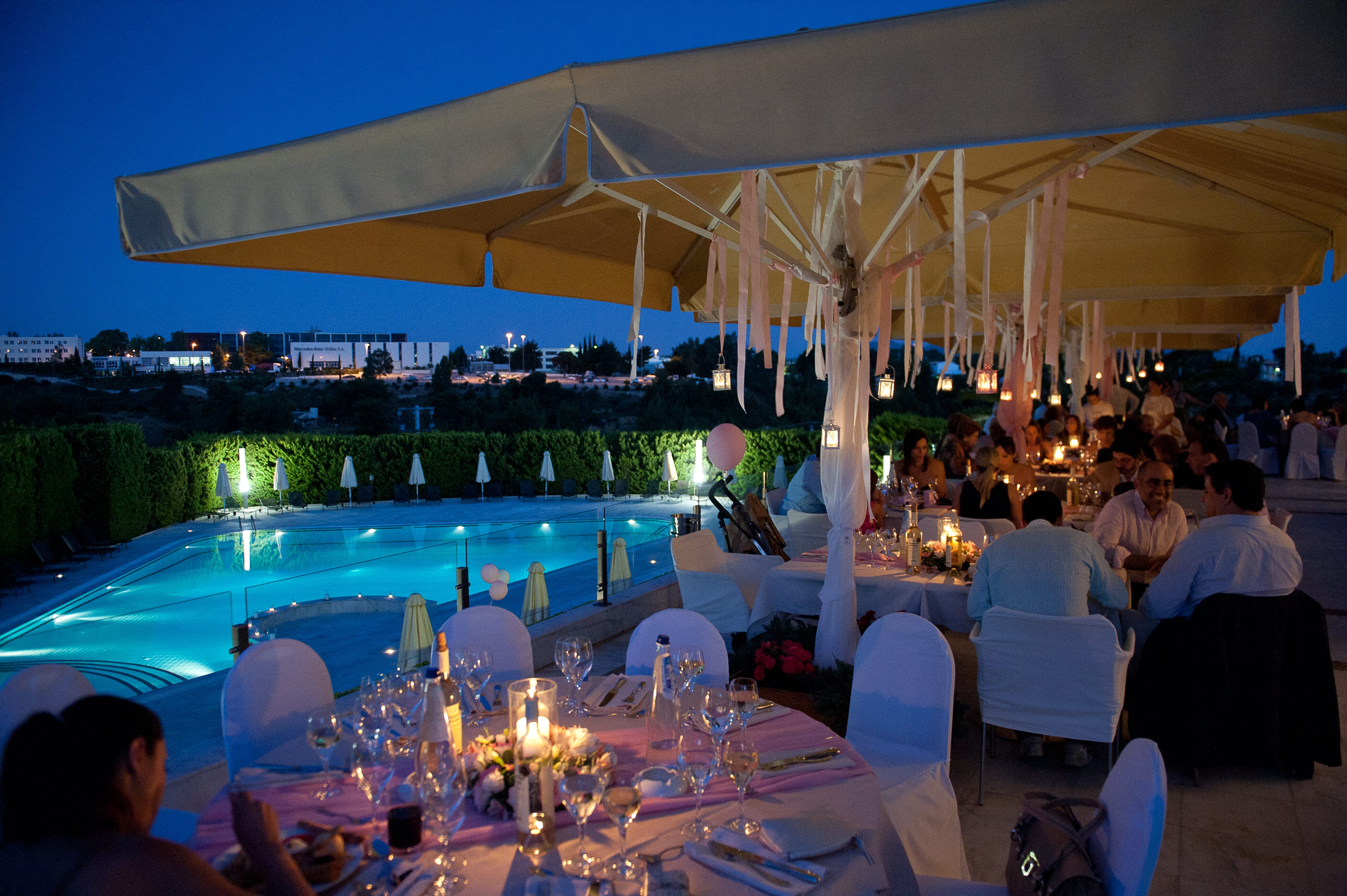 a large group of people sitting at a table with a pool and chairs