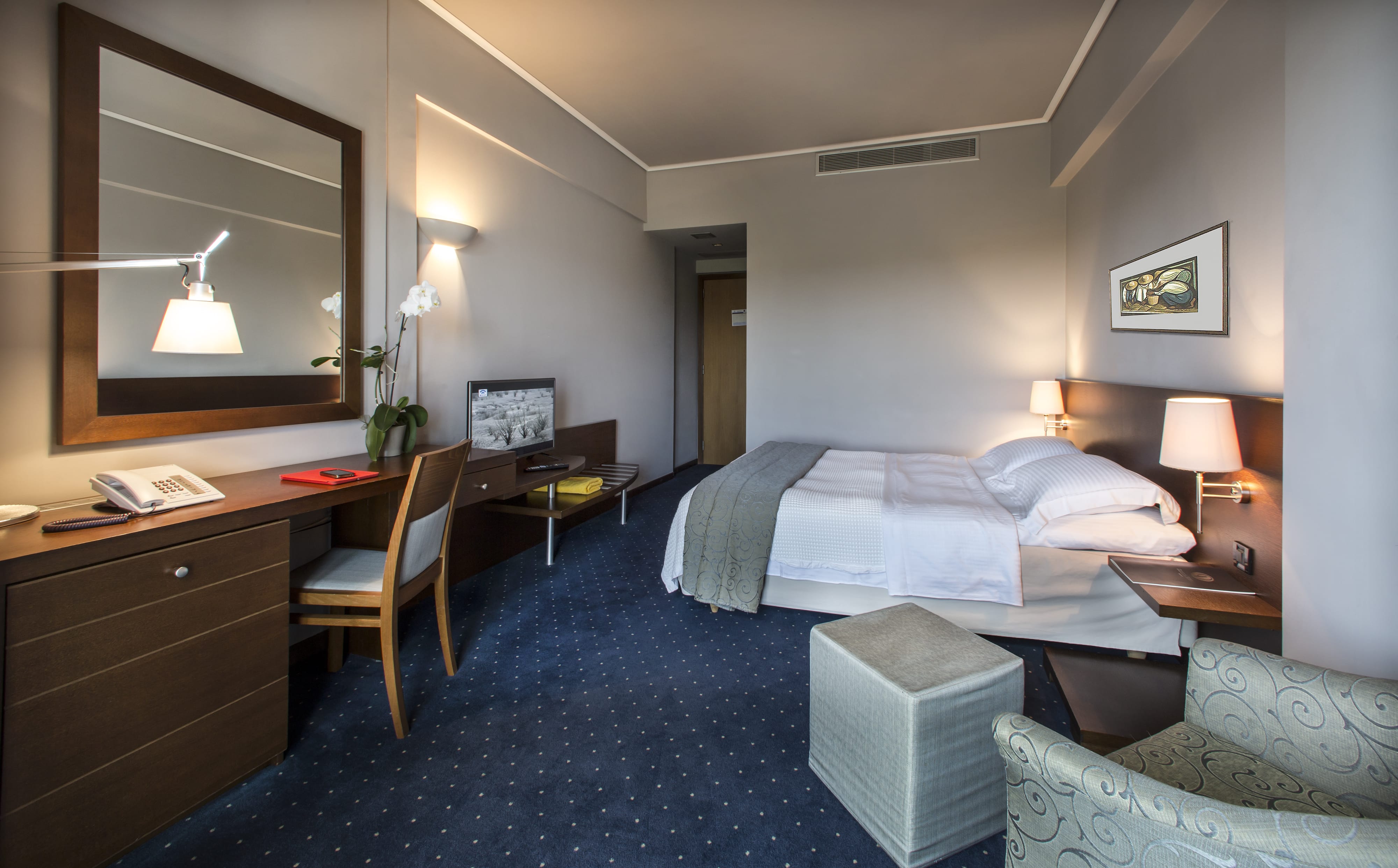 a hotel room with a bed desk and a mirror