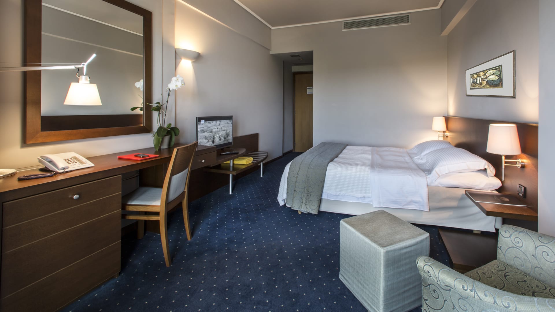 a hotel room with a bed desk and a mirror