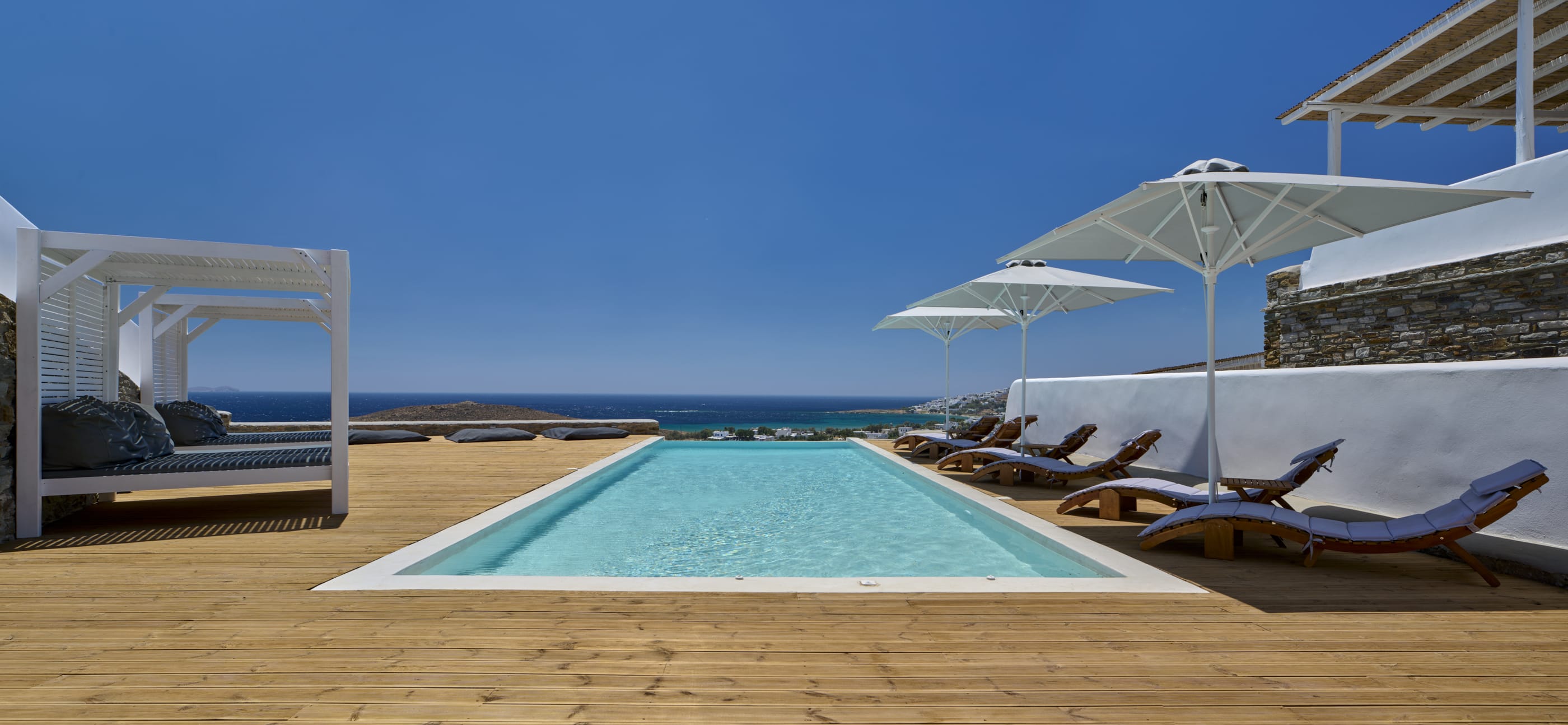a pool with lounge chairs and umbrellas by a beach