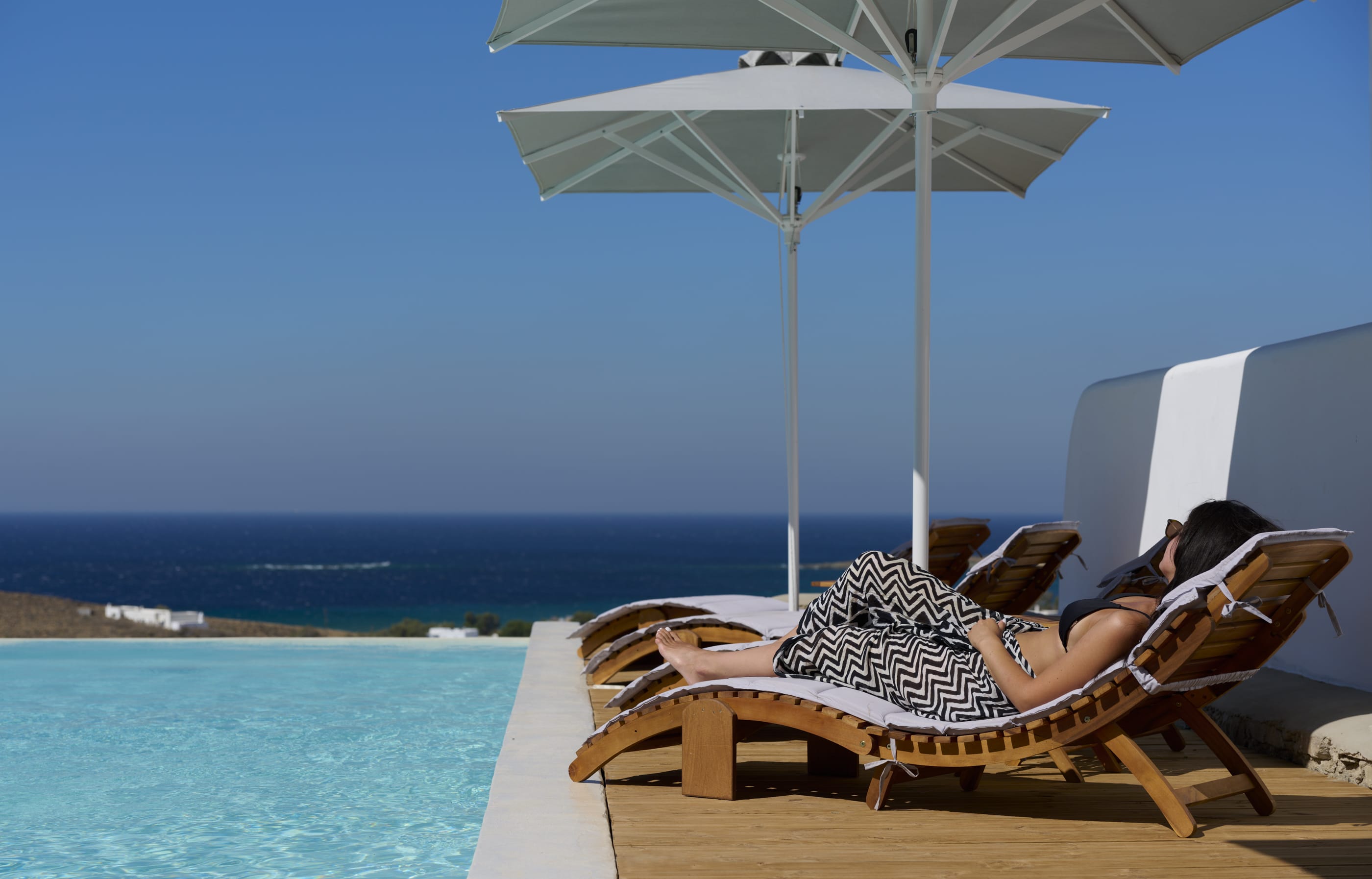 a person lying in a lounge chair under an umbrella on a deck