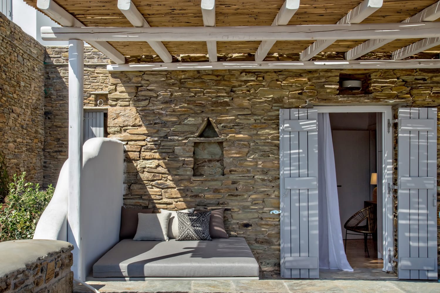 a patio with a stone wall and a stone patio with a white chair
