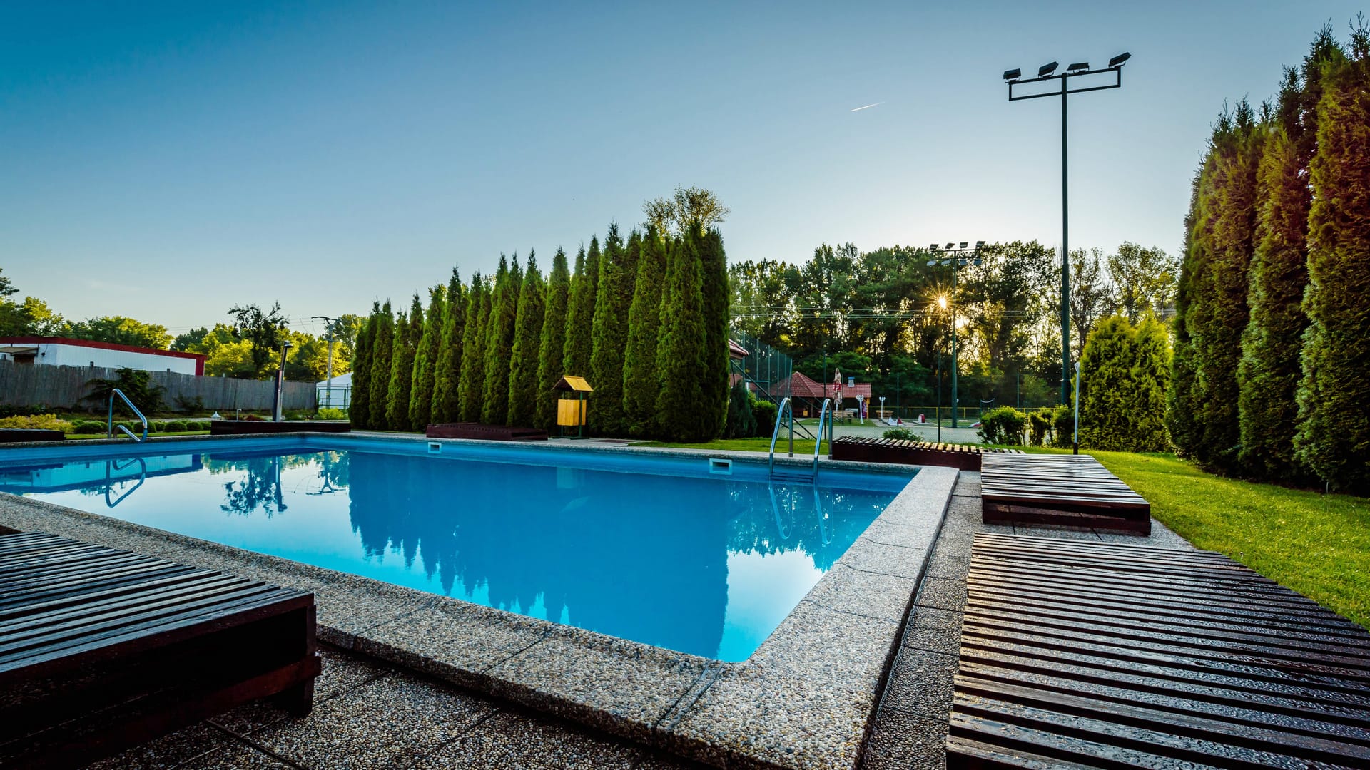 a swimming pool with trees and grass