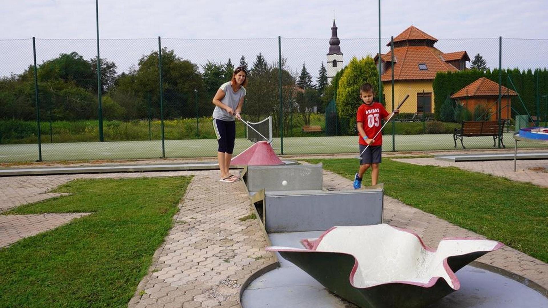 a couple of people running on a path with a slide and a building in the background