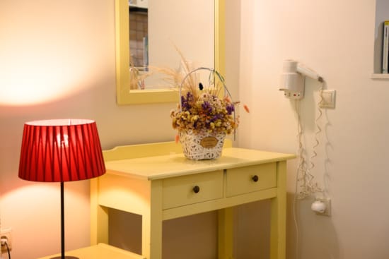a lamp next to a desk with a vase of flowers