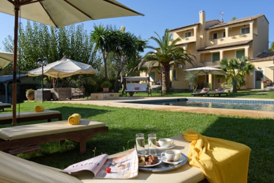 a table with food and drinks on it by a lawn with buildings