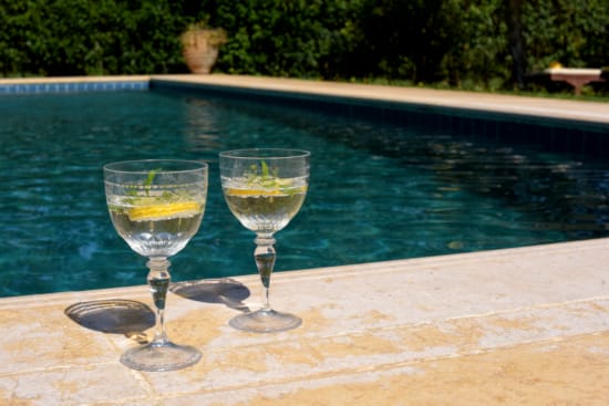 two glasses of wine by a pool
