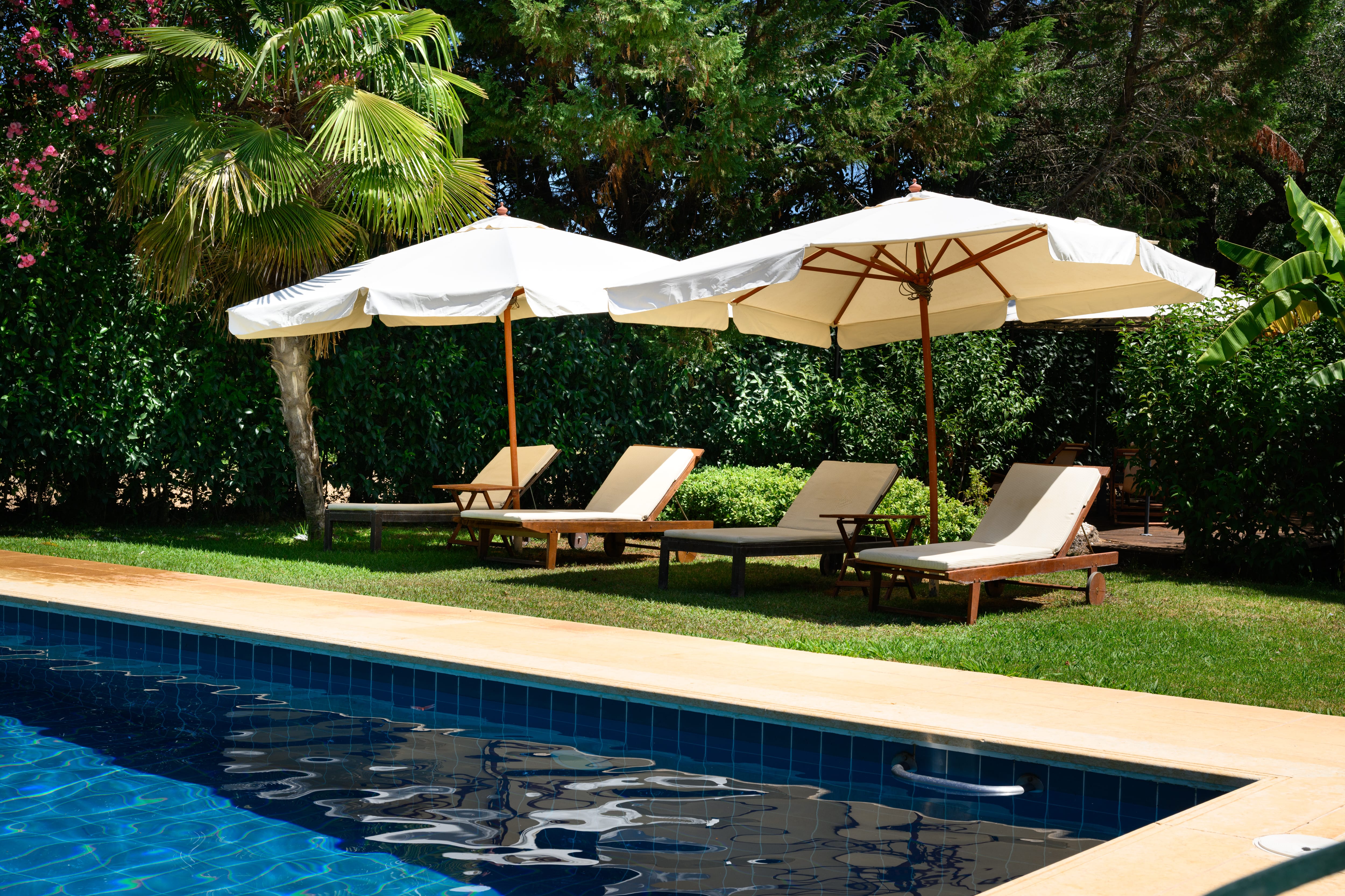 a pool with lounge chairs and umbrellas by it