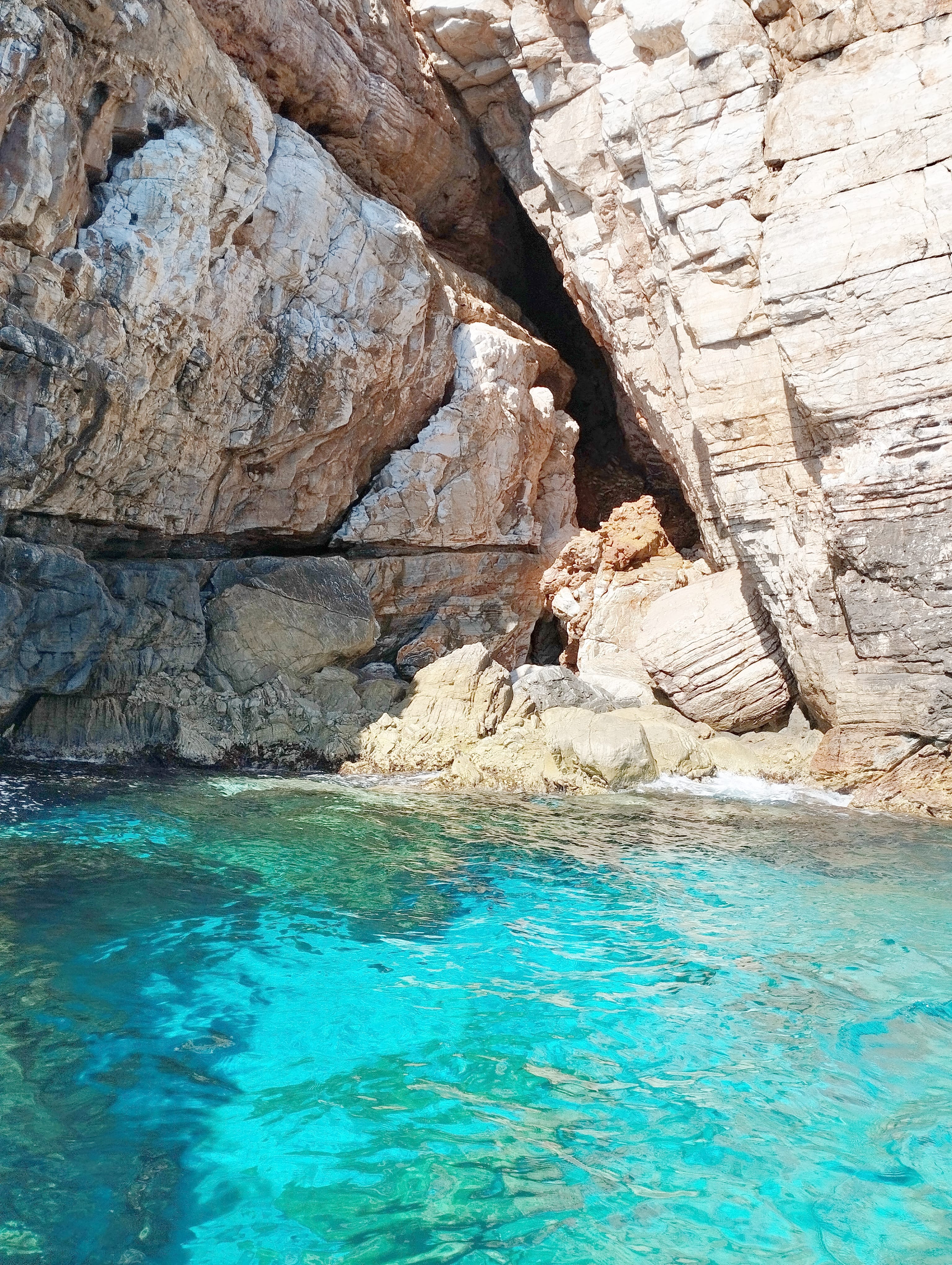 a body of water with a rock wall and a cave
