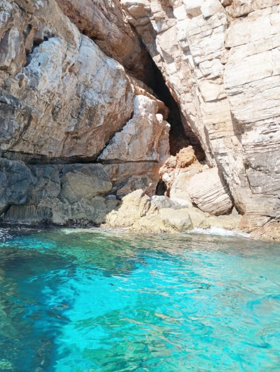 a body of water with a rock wall and a cave