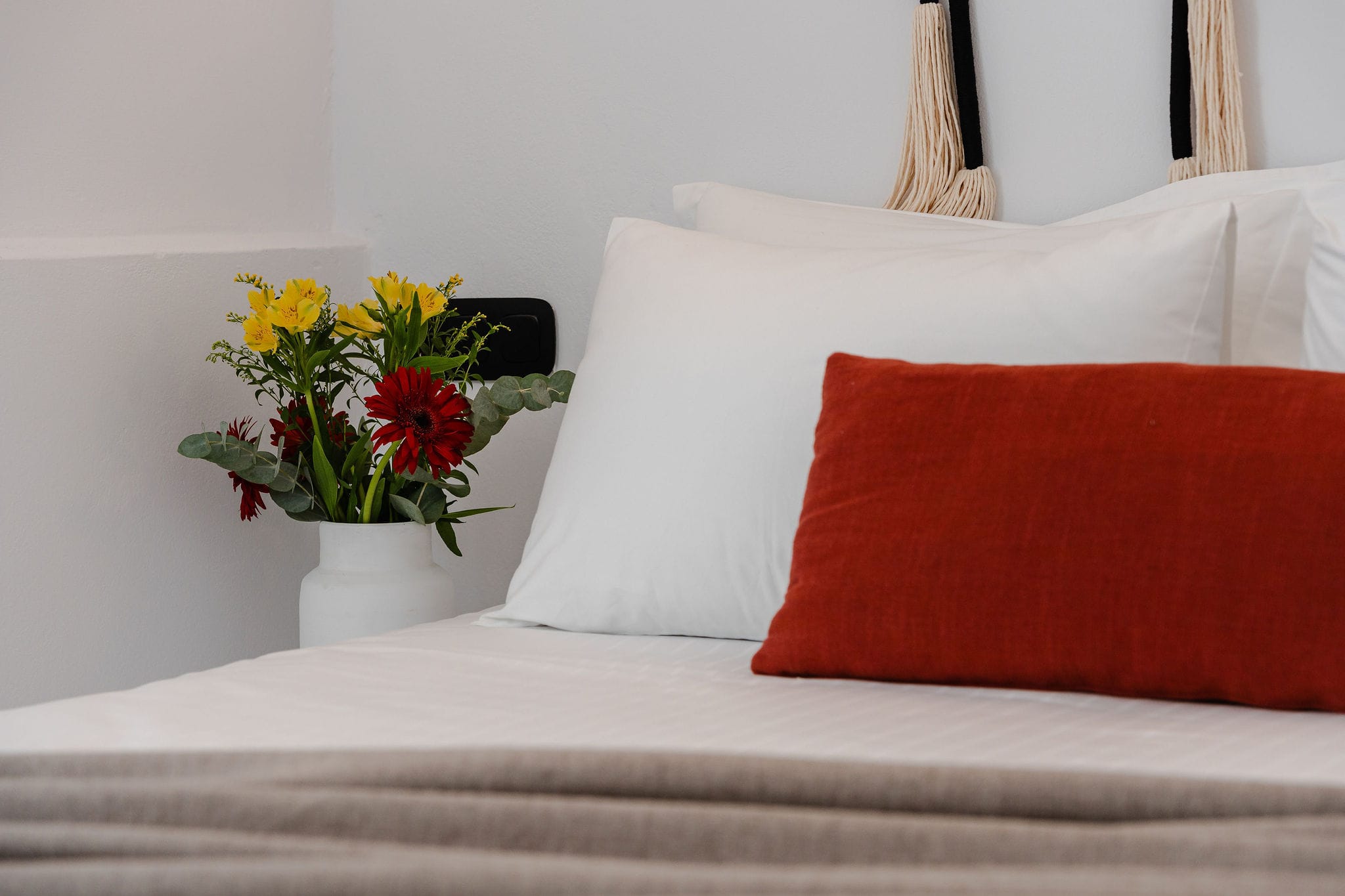 a white bed with red pillows