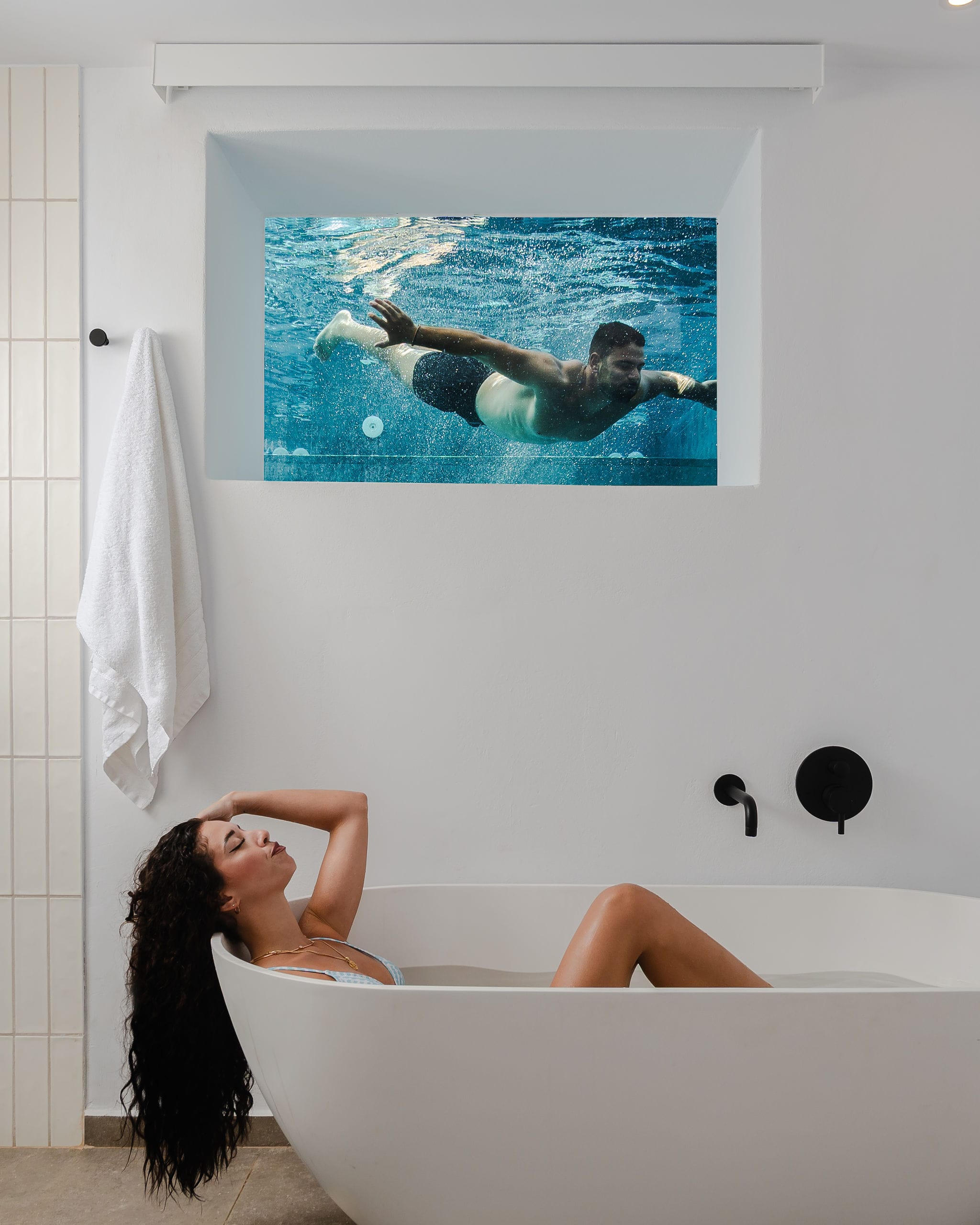 a person lying in a bathtub with a picture on the wall